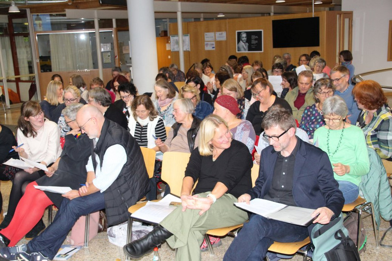 Iris Macke und Axel Reimann (vordere Reihe rechts) vom Andere Zeiten Team und diskutierende Teilnehmende bei "Mini-Redaktionskonferenz" - Welcher Text soll es in den Kalender schaffen? 